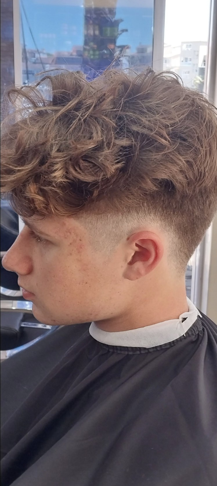 Textured curly top with a low fade — recent haircut at Bay Barber.